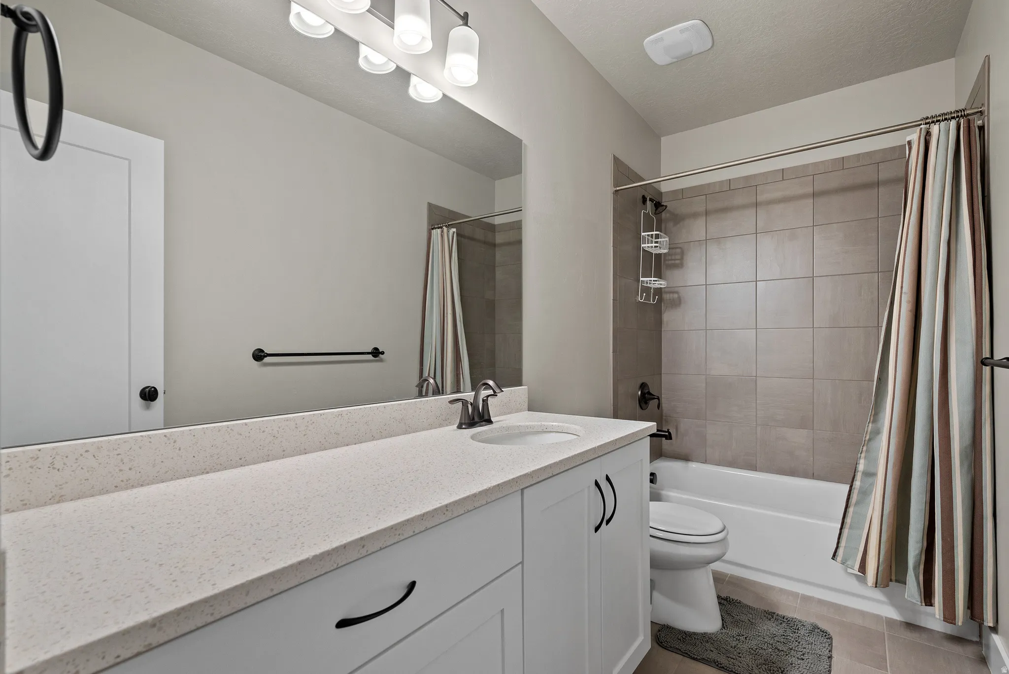 Full bath with vanity, shower / tub combo, and light tile patterned floors