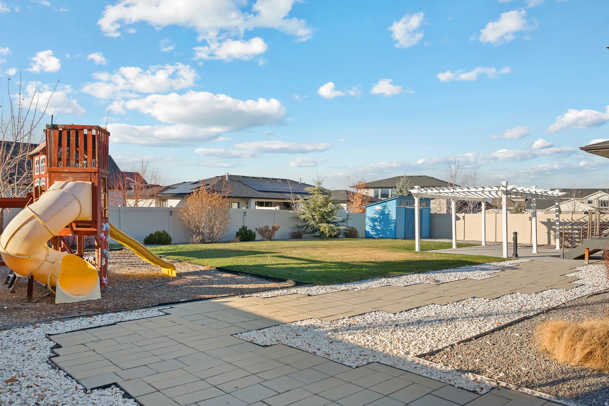 View of play area with a storage shed, a pergola, a fenced backyard, a patio area, and a residential view