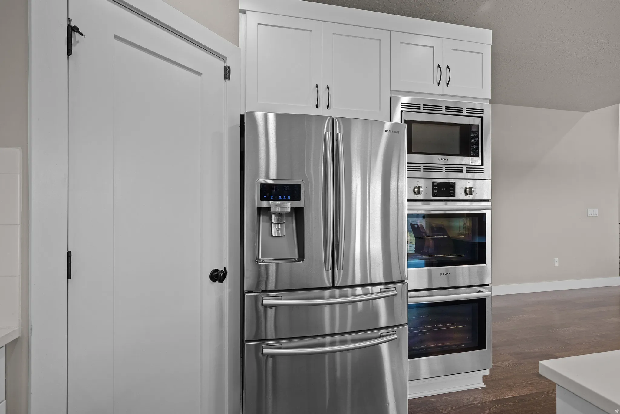 Kitchen featuring stainless steel appliances, white cabinets, and dark wood-type flooring