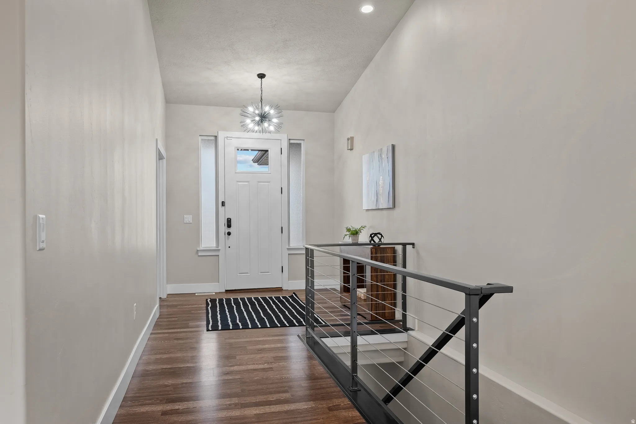 Entryway with dark wood finished floors and a chandelier