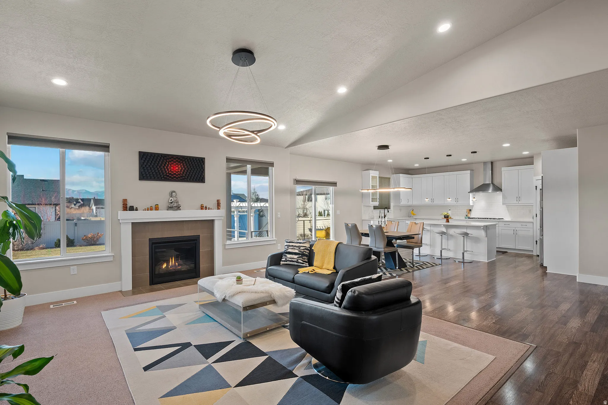 Living area with recessed lighting, a tiled fireplace, plenty of natural light, a textured ceiling, and vaulted ceiling