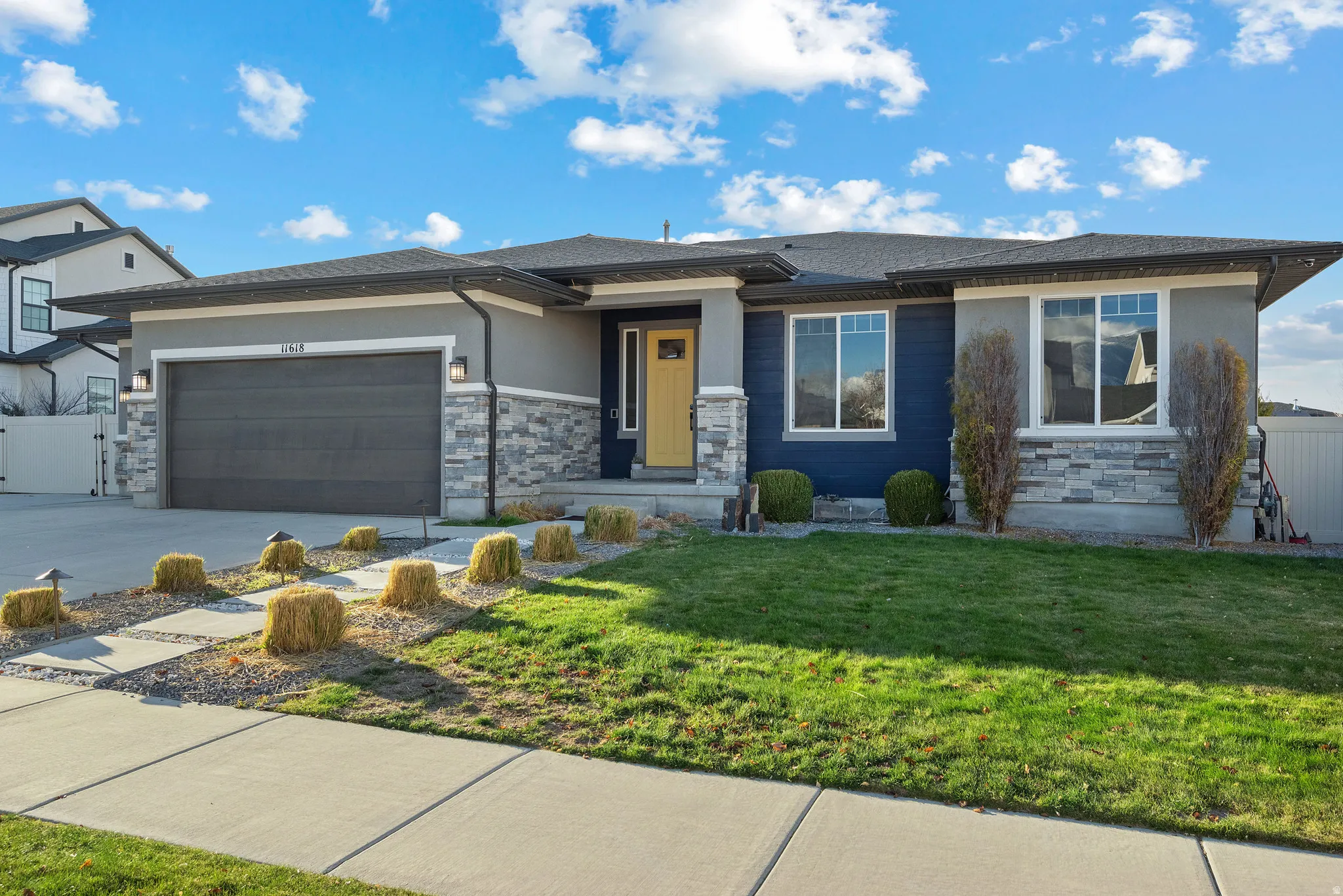 Prairie-style house featuring stone siding, a garage, a shingled roof, stucco siding, and concrete driveway
