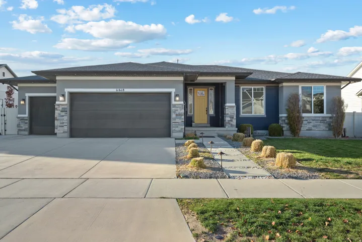 Prairie-style home with stone siding, a garage, concrete driveway, a front yard, and stucco siding