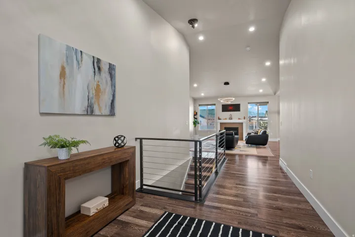 Corridor with an upstairs landing, recessed lighting, dark wood-style flooring, and a high ceiling