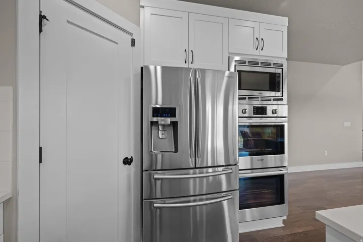 Kitchen featuring stainless steel appliances, white cabinets, and dark wood-type flooring