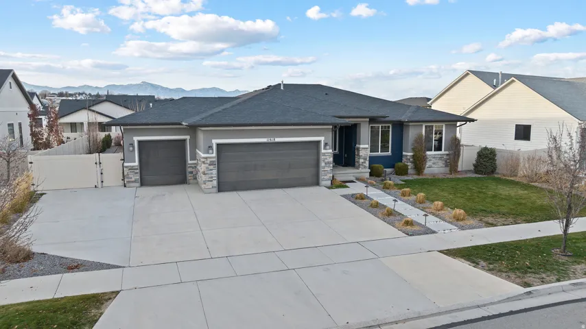 View of front of home with an attached garage, a gate, concrete driveway, and roof with shingles