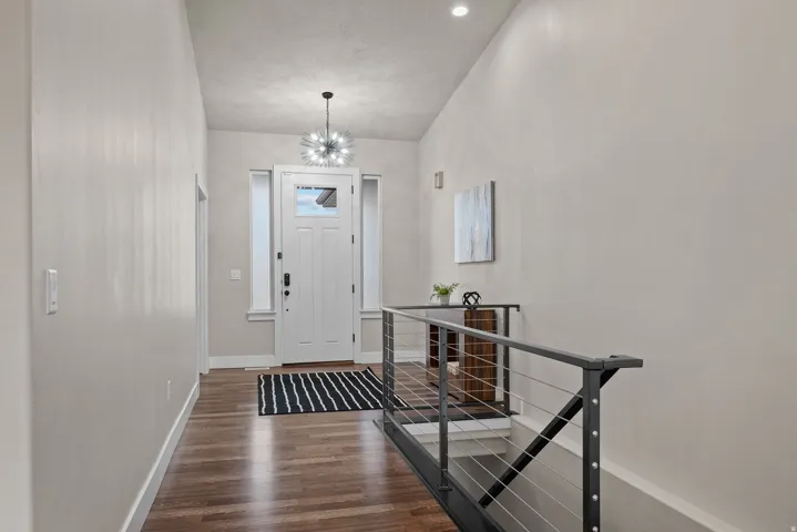 Entryway with dark wood finished floors and a chandelier