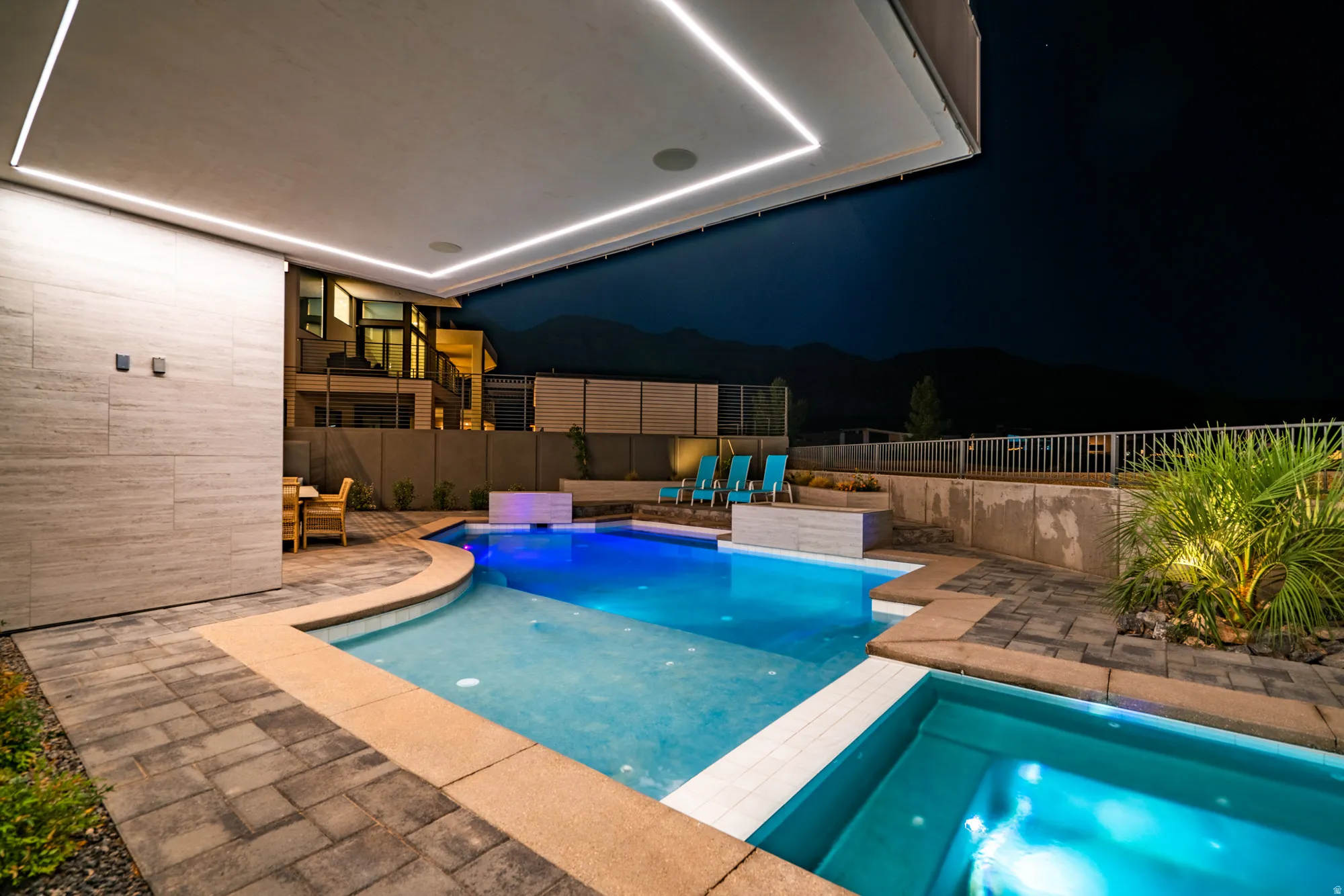 Pool at twilight with a hot tub, a patio area, and a fenced backyard