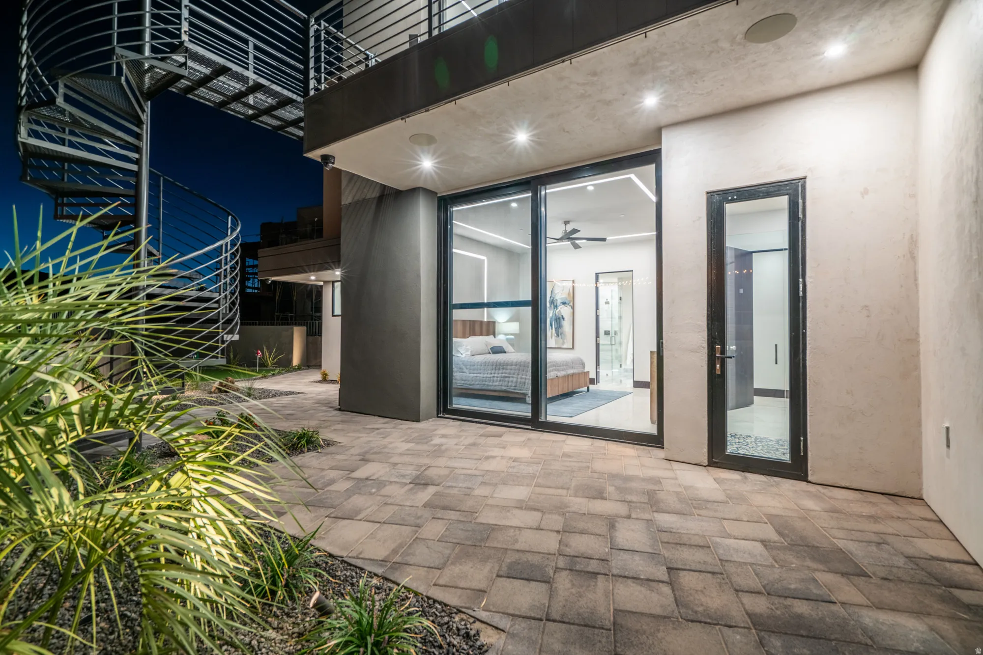 Exterior entry at night featuring a patio and stucco siding