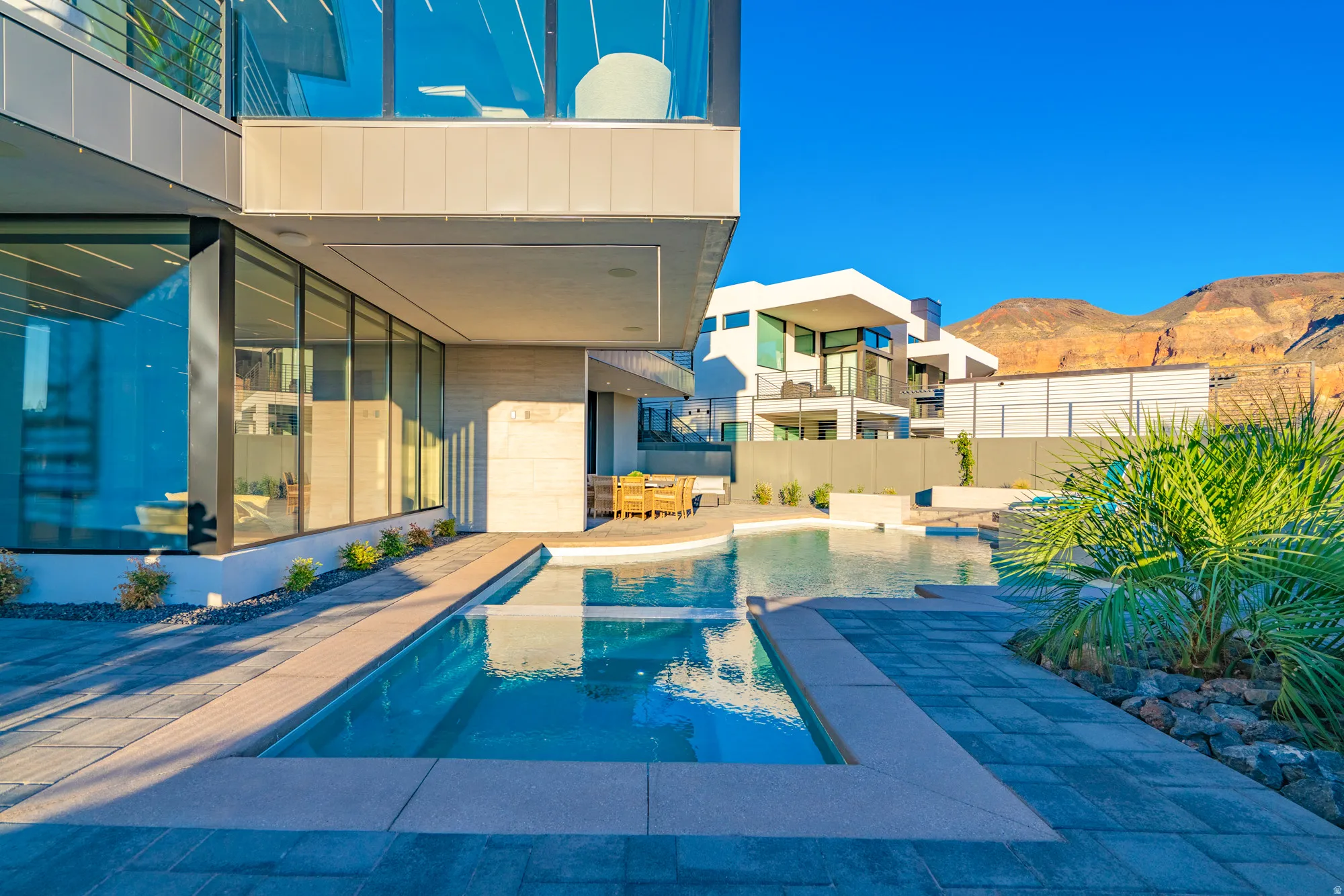 View of swimming pool featuring a patio, a balcony, a mountain view, a pool with connected hot tub, and outdoor dining area