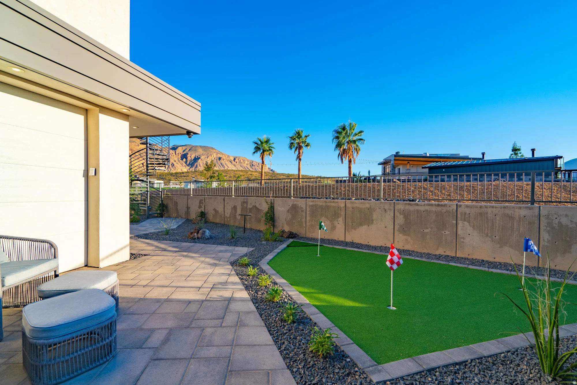 Fenced backyard featuring a putting green, a mountain view, and a patio