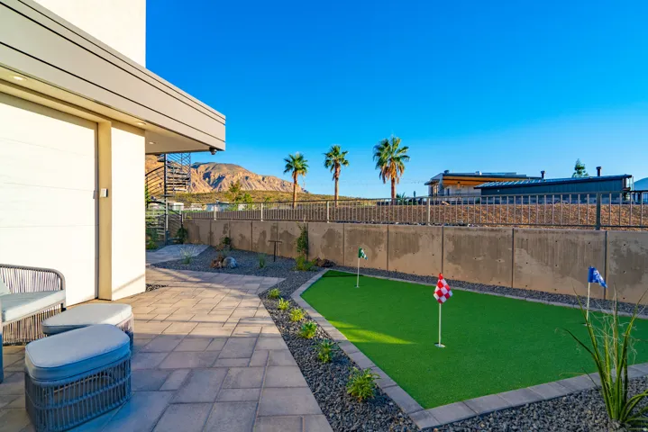 Fenced backyard featuring a putting green, a mountain view, and a patio