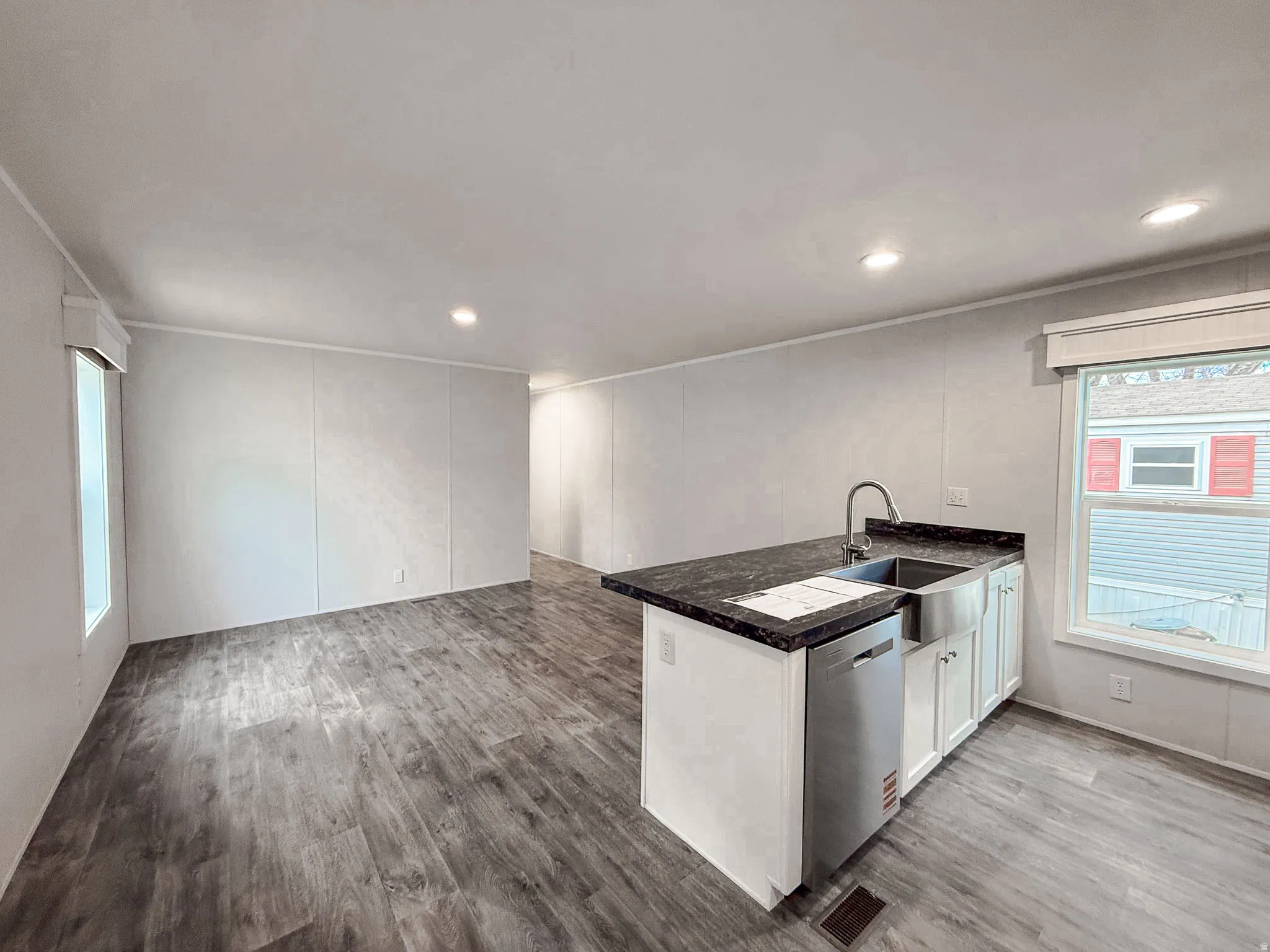 Kitchen with a peninsula, light wood finished floors, white cabinetry, a decorative wall, and open floor plan