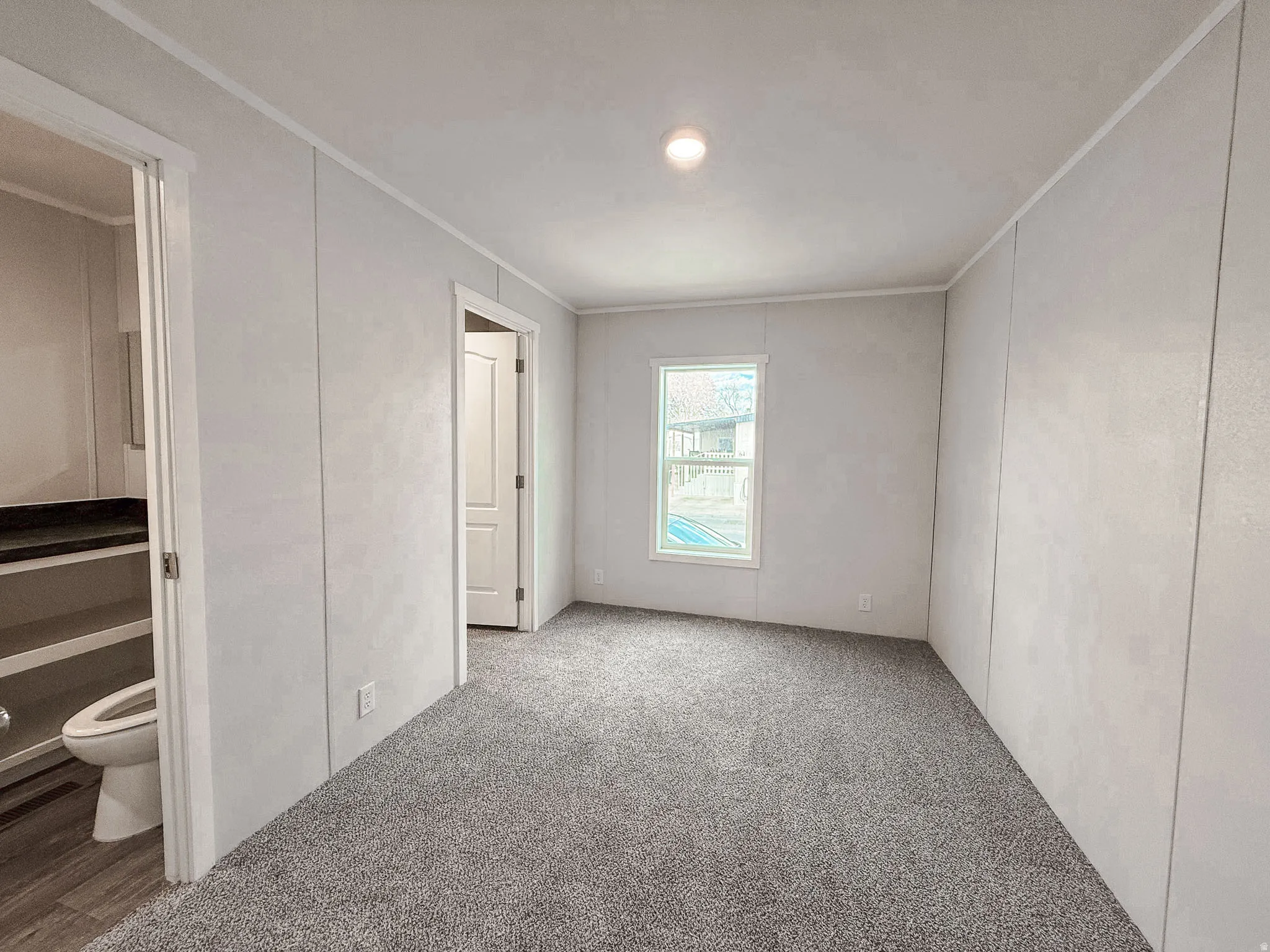 Unfurnished bedroom with crown molding, carpet flooring, and ensuite bath
