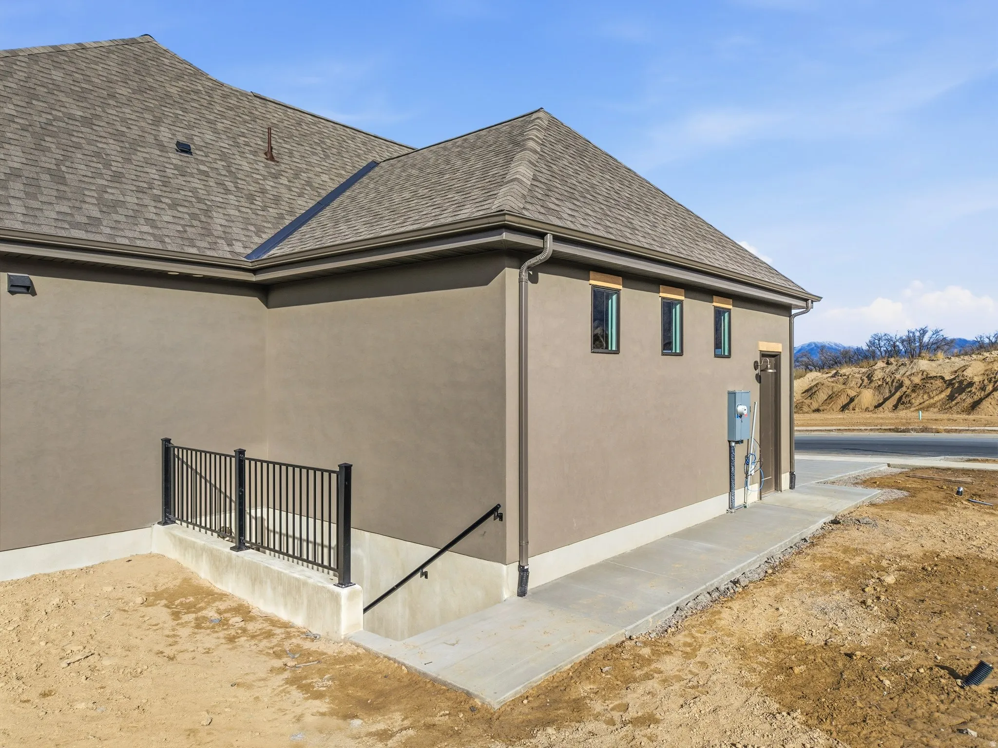 View of side of home with stucco siding and roof with shingles