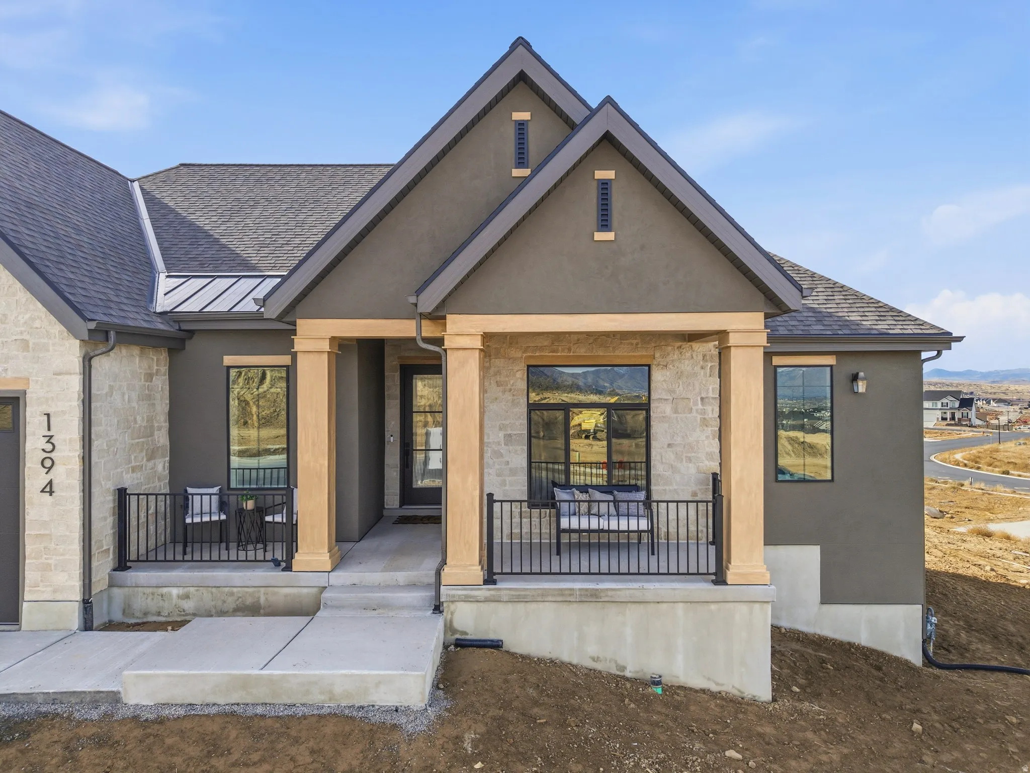 View of front facade featuring stone siding, a porch, and stucco siding