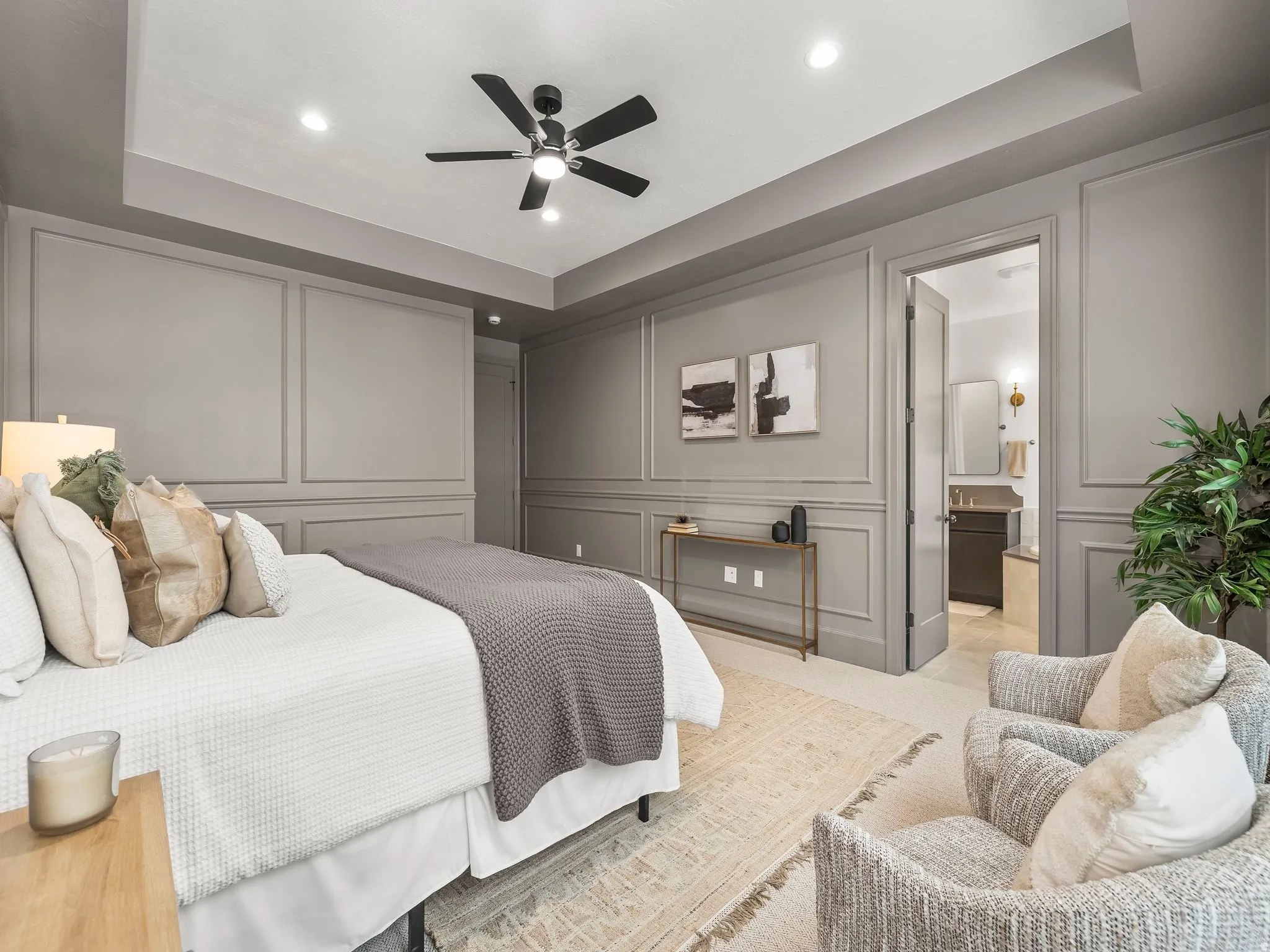 Carpeted bedroom featuring a decorative wall, a raised ceiling, ceiling fan, recessed lighting, and ensuite bathroom