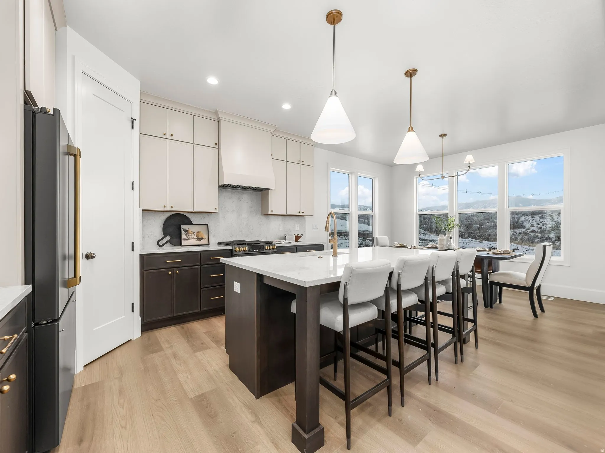 Kitchen with a breakfast bar area, dark brown cabinets, hanging light fixtures, freestanding refrigerator, and a kitchen island with sink