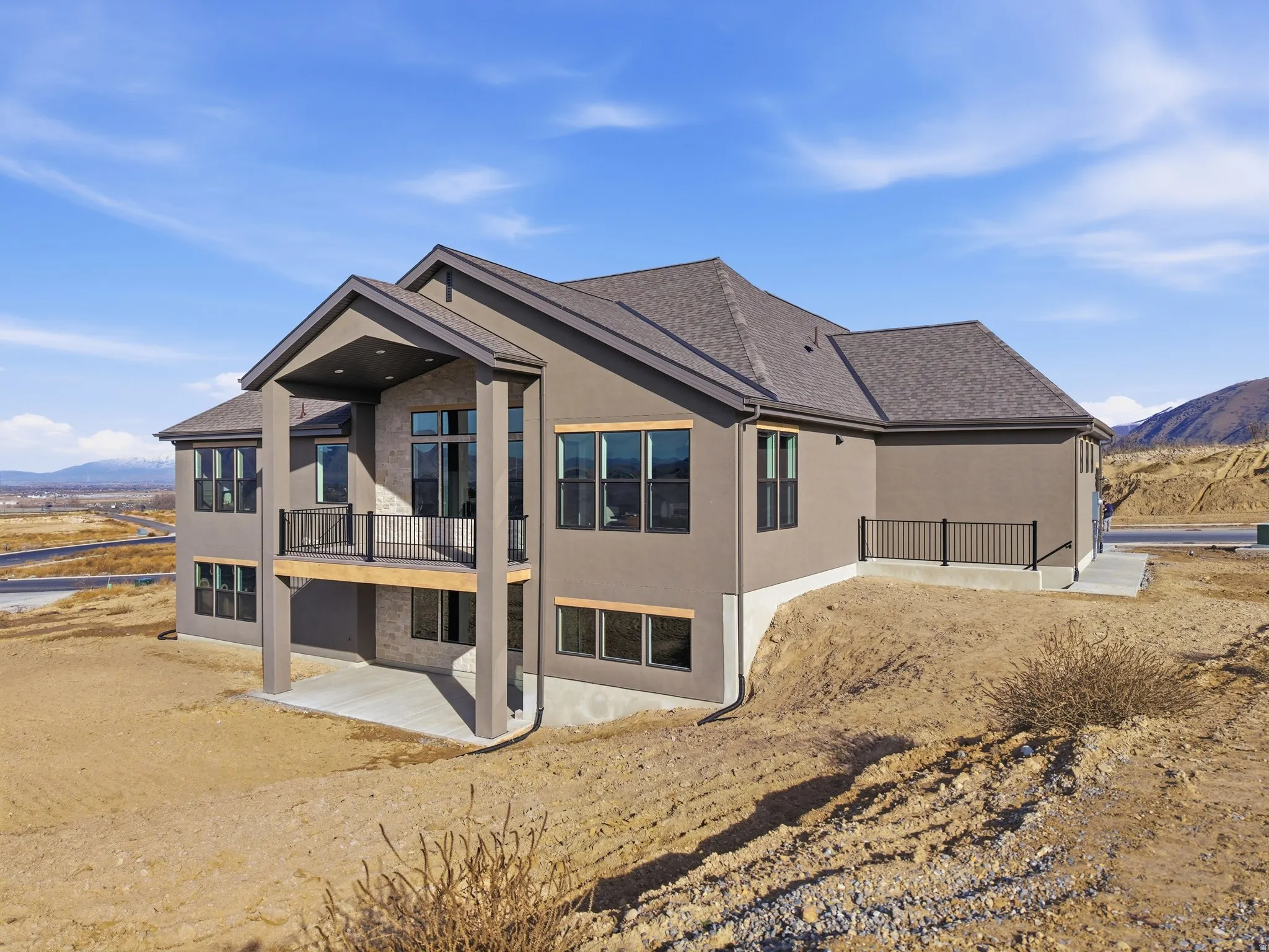 Back of property with a mountain view, a patio, stucco siding, and a balcony