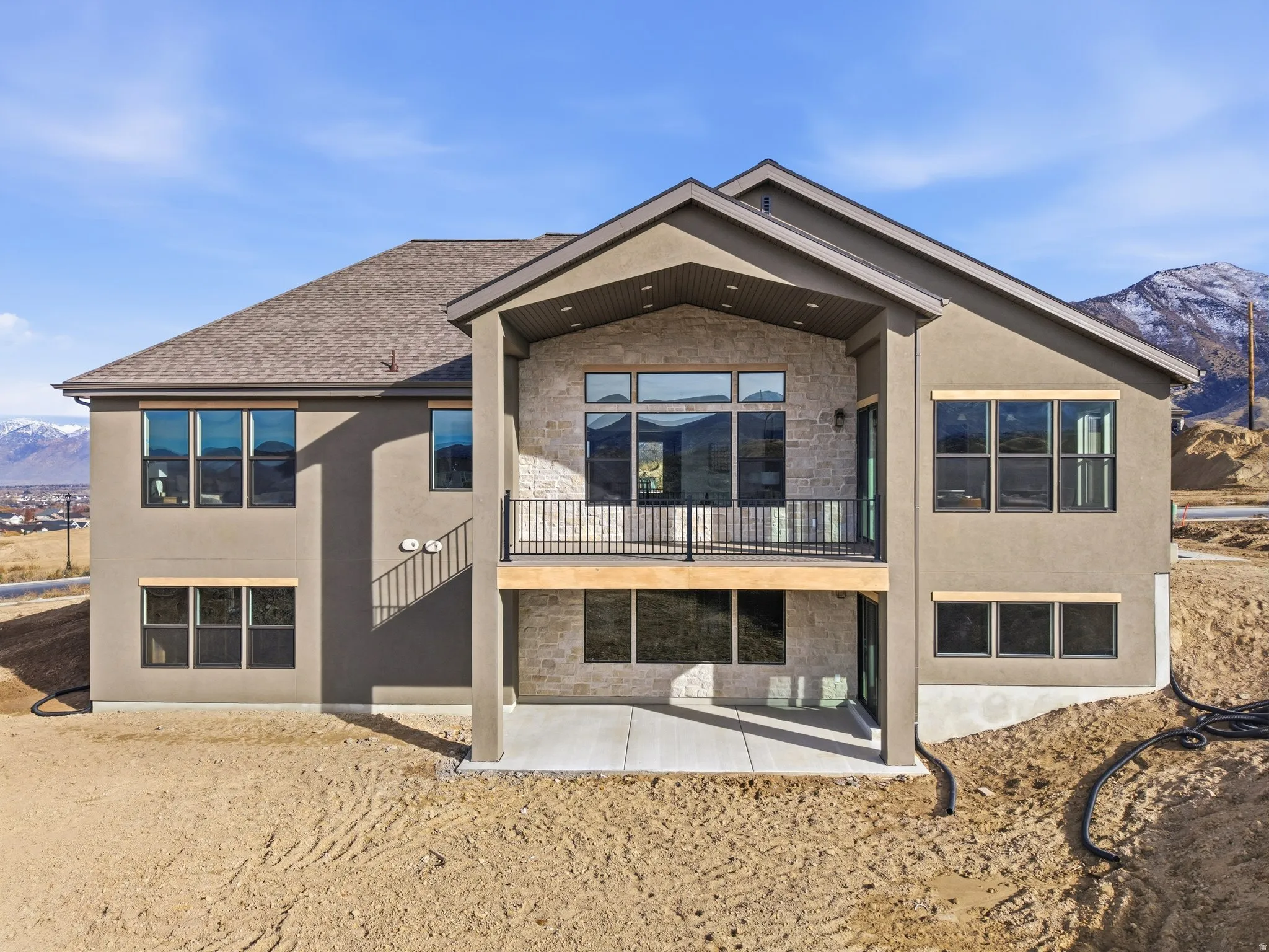 Rear view of property featuring a mountain view, a patio area, stone siding, and stucco siding