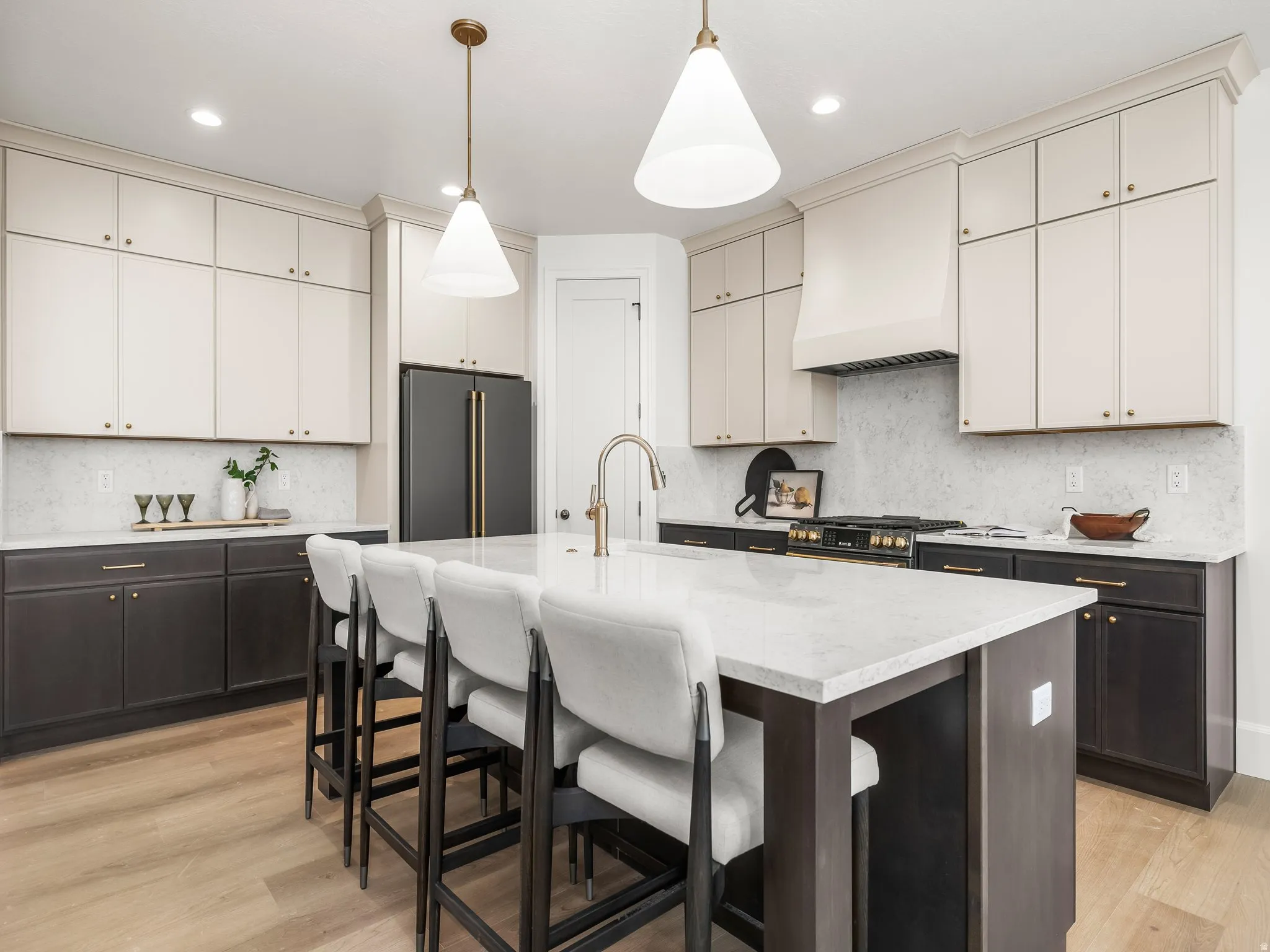 Kitchen featuring hanging light fixtures, high end appliances, light stone countertops, premium range hood, and a kitchen breakfast bar