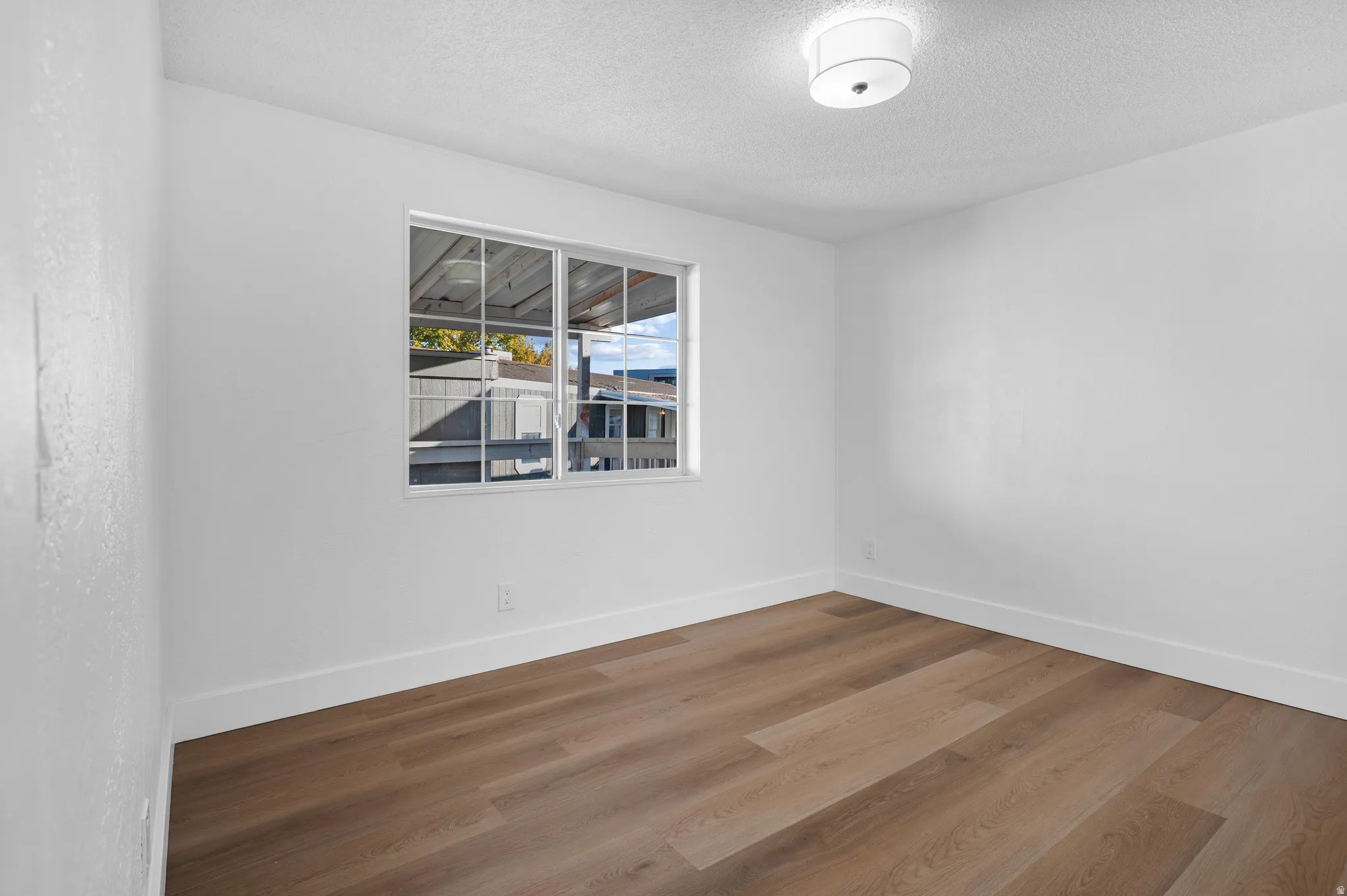 Empty room featuring wood finished floors and a textured ceiling