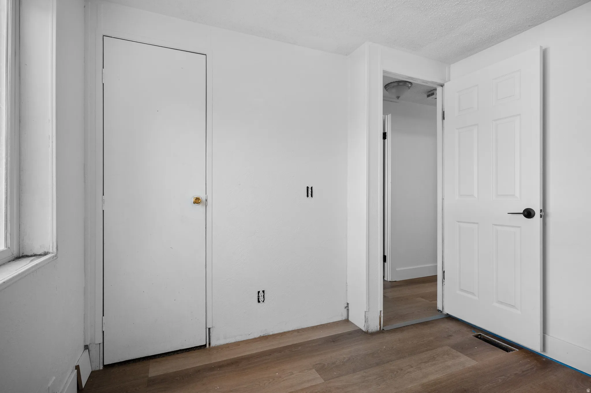 Unfurnished bedroom with dark wood-style flooring and a textured ceiling