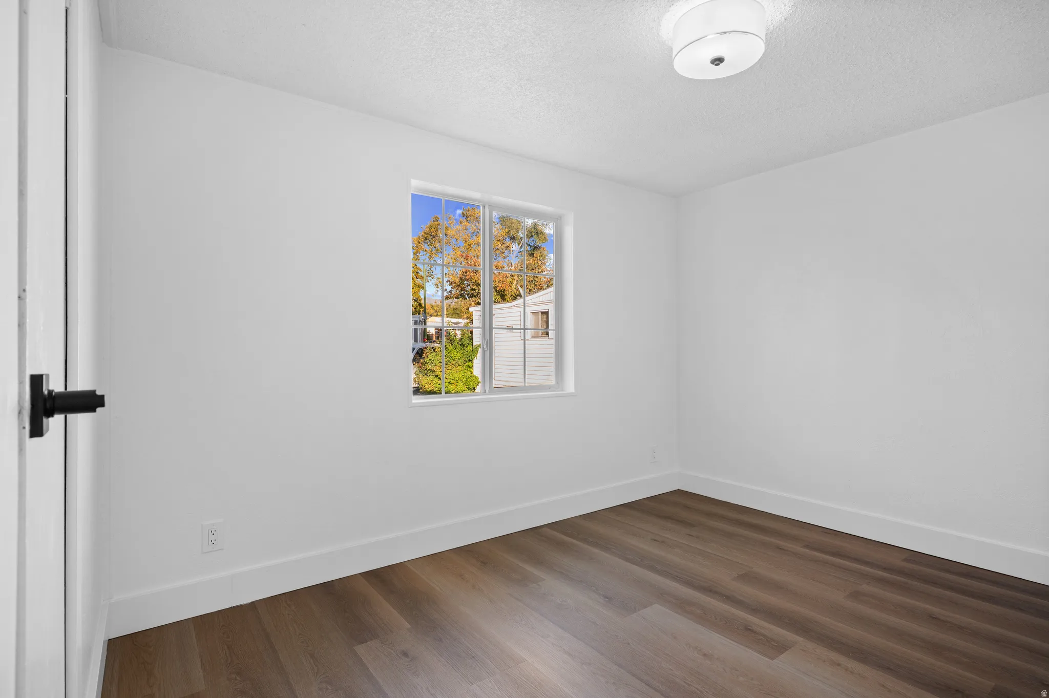 Unfurnished room featuring wood finished floors and a textured ceiling