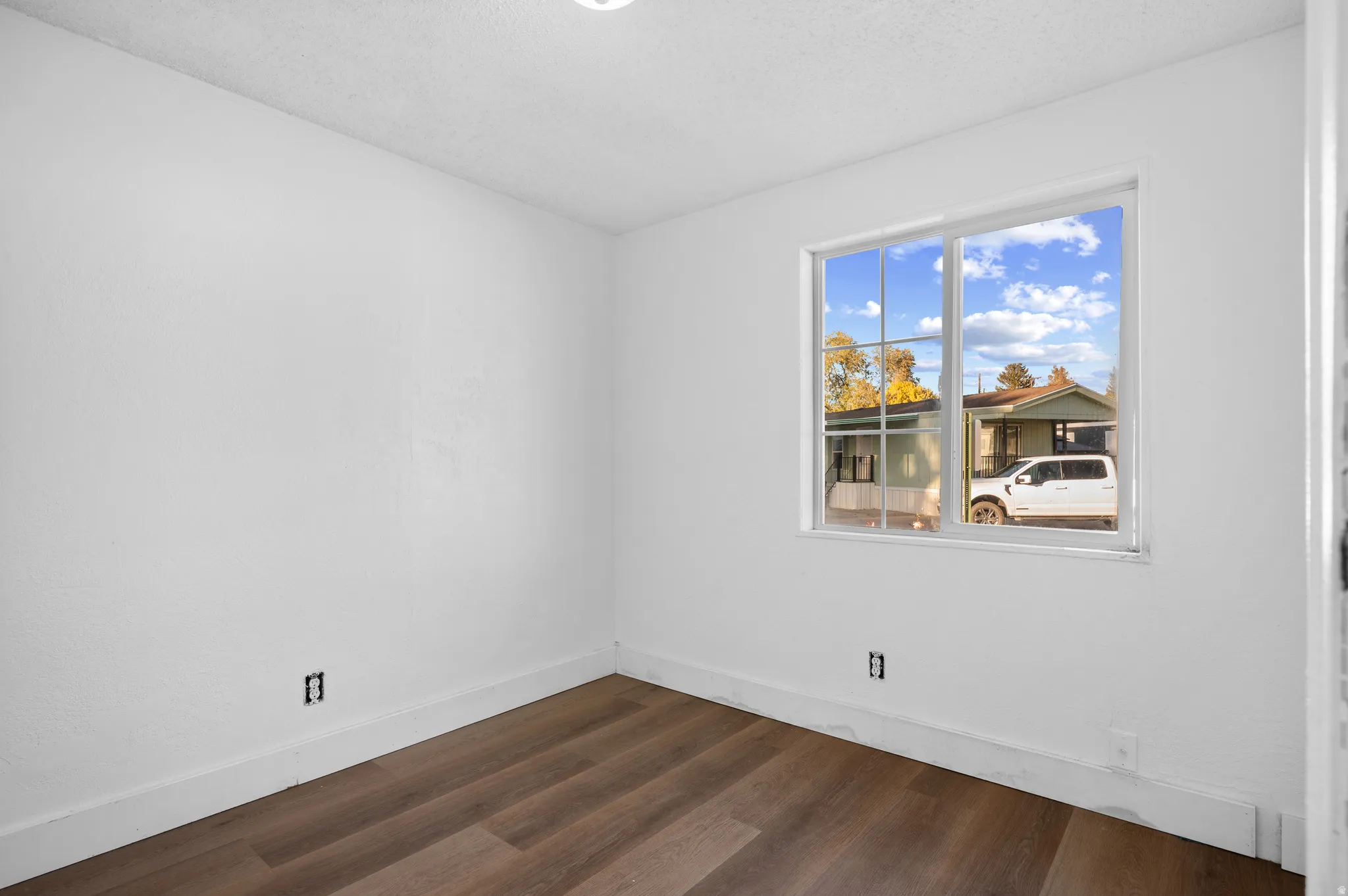 Unfurnished room with dark wood-style floors and a textured ceiling