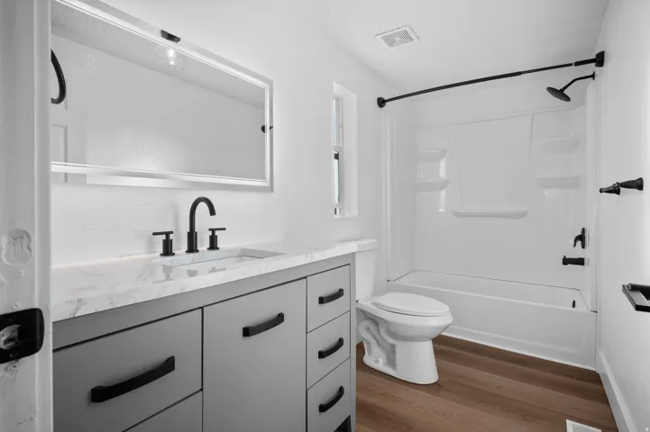 Full bathroom featuring vanity, dark wood-style flooring, and  shower combination