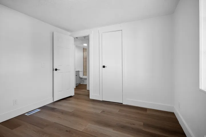 Unfurnished bedroom with dark wood-style flooring, a textured ceiling, and a closet