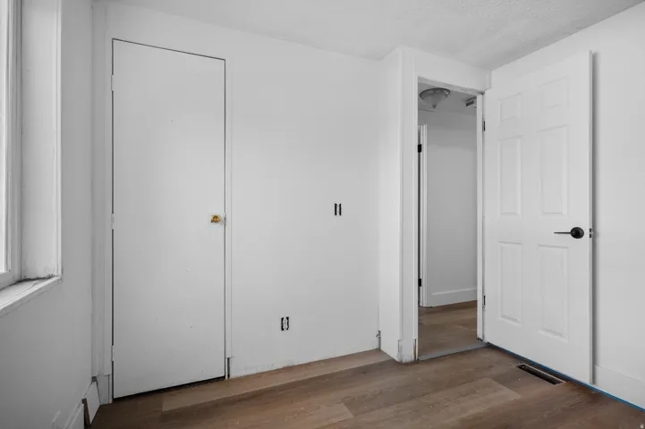 Unfurnished bedroom with dark wood-style flooring and a textured ceiling