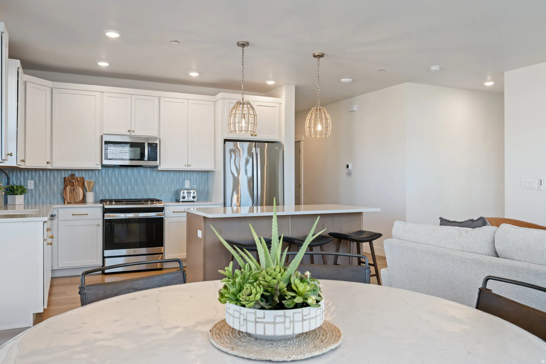 Kitchen with light wood-style floors, stainless steel appliances, a breakfast bar, a center island, and two tone color scheme