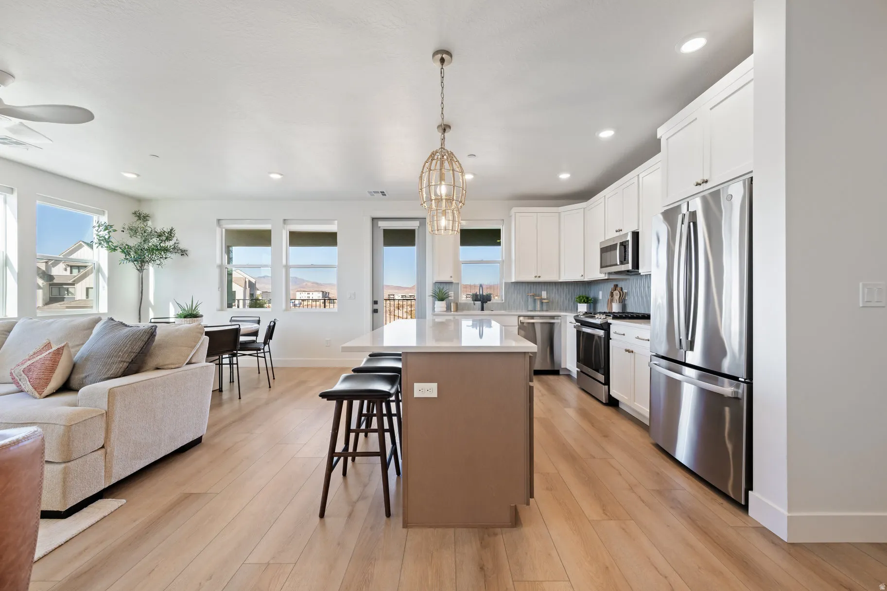 Kitchen featuring open floor plan, stainless steel appliances, a kitchen island, light wood finished floors, and two tone color scheme