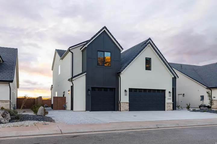 Modern farmhouse with board and batten siding, a garage, driveway, and stone siding