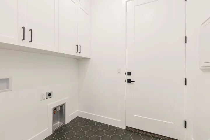 Laundry room featuring hookup for an electric dryer, cabinet space, washer hookup, and dark tile patterned flooring