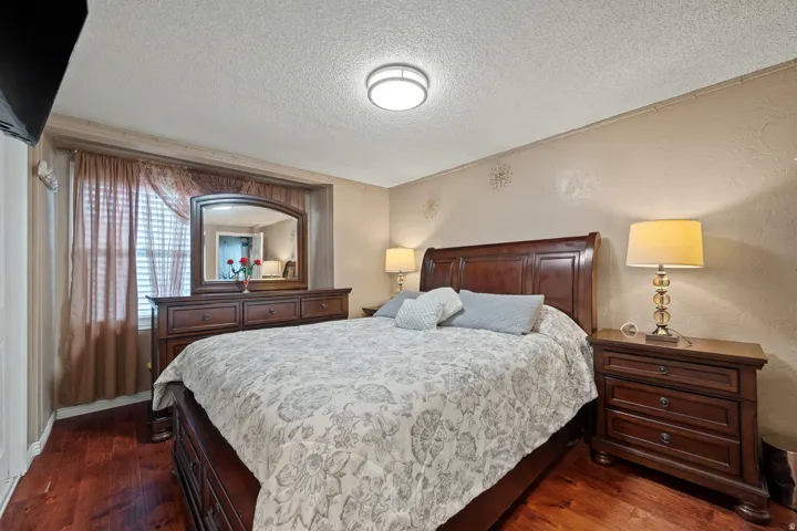 Bedroom featuring a textured ceiling, dark wood-style floors, and a textured wall