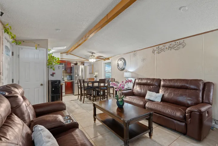 Living room featuring a textured ceiling, light tile patterned floors, and a ceiling fan
