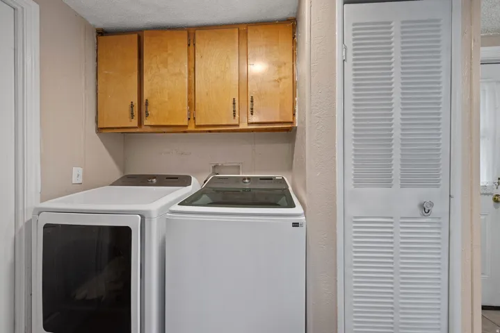 Laundry room with cabinet space, a heating unit, washing machine and dryer, and a textured ceiling