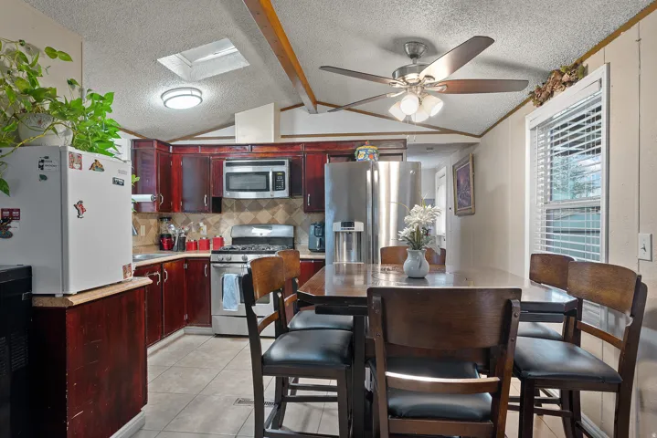 Kitchen featuring appliances with stainless steel finishes, a textured ceiling, light tile patterned floors, light countertops, and ceiling fan