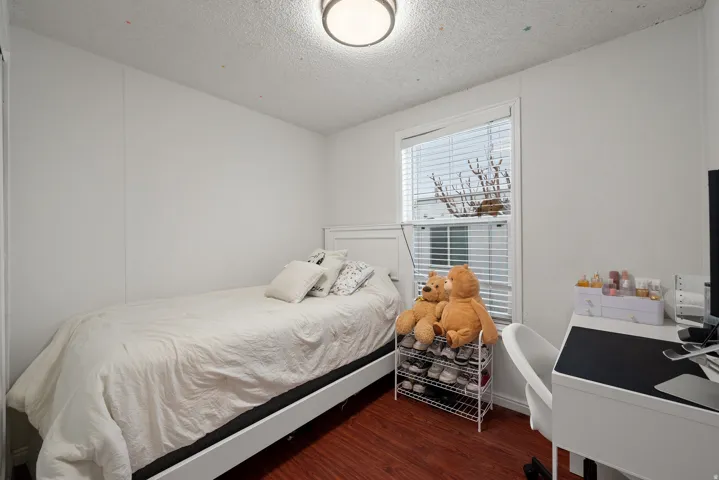 Bedroom featuring dark wood-style floors, a textured ceiling, and an office area