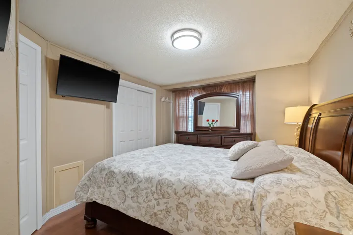 Bedroom with a closet, a textured ceiling, and dark wood-style flooring