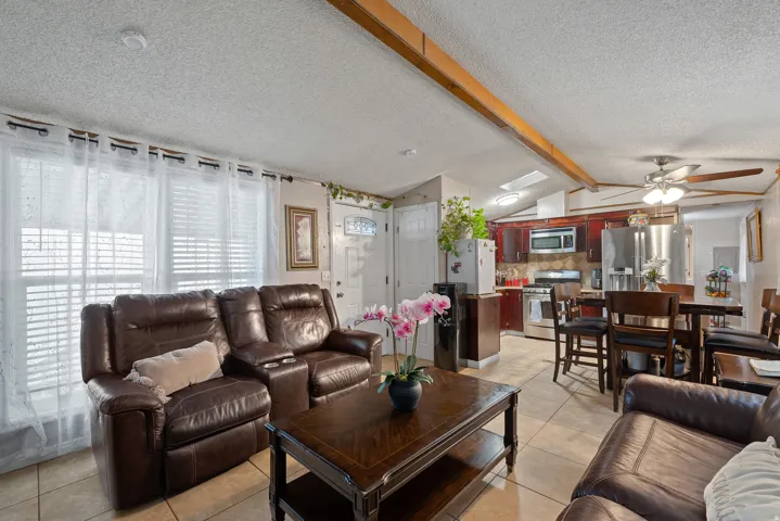 Living room featuring light tile patterned floors, a textured ceiling, and a ceiling fan