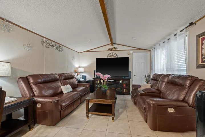 Living area featuring a textured ceiling, light tile patterned floors, and a textured wall