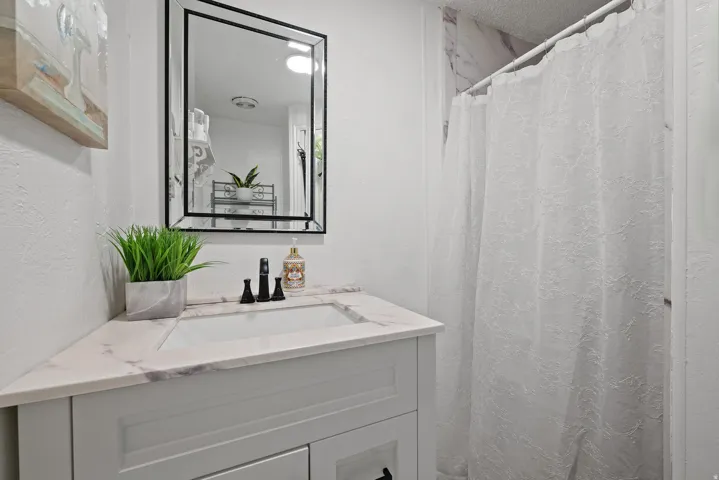 Full bath featuring a stall shower, vanity, and a textured wall