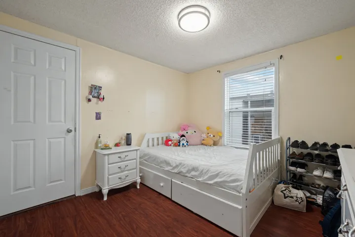 Bedroom with a textured ceiling and dark wood-type flooring