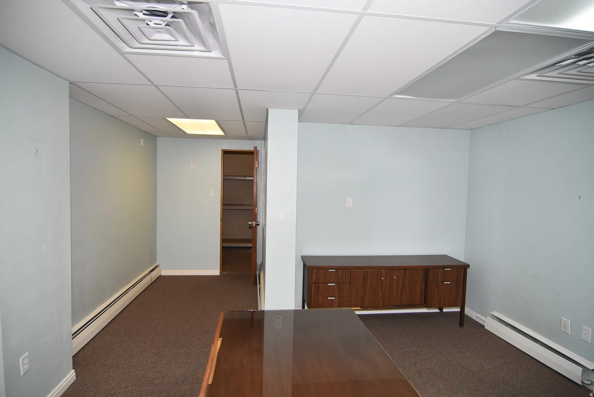 Carpeted spare room with a baseboard heating unit and a drop ceiling