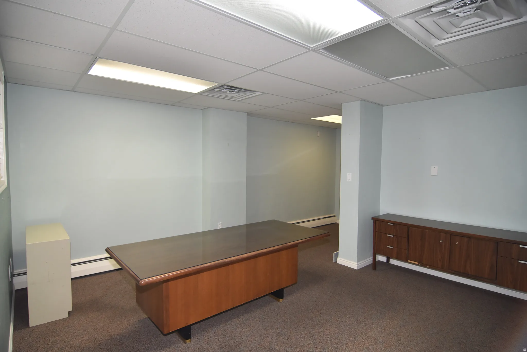 Unfurnished office featuring a baseboard radiator and a paneled ceiling