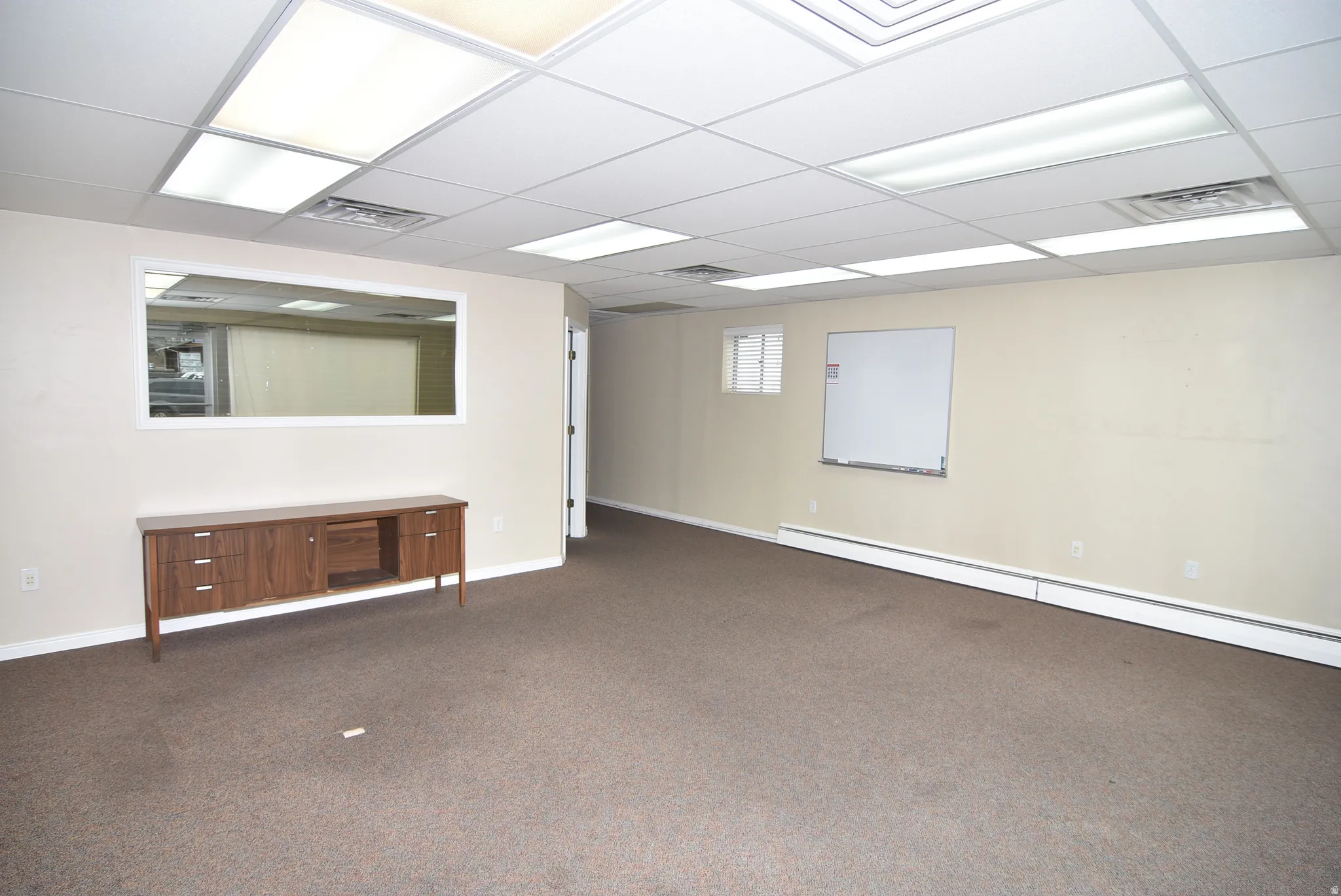 Basement with a baseboard heating unit, carpet, and a paneled ceiling