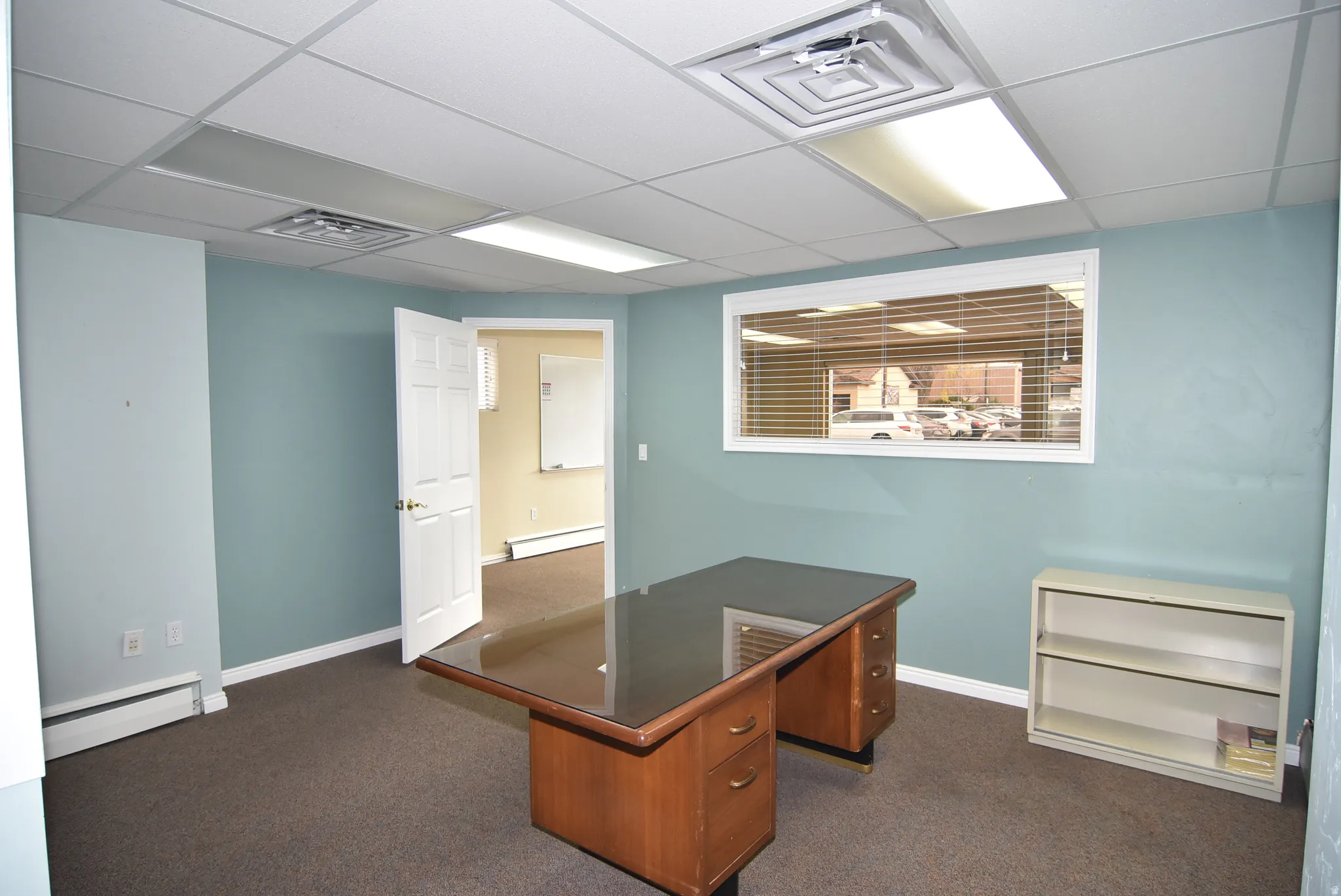 Unfurnished office with a baseboard heating unit and a drop ceiling